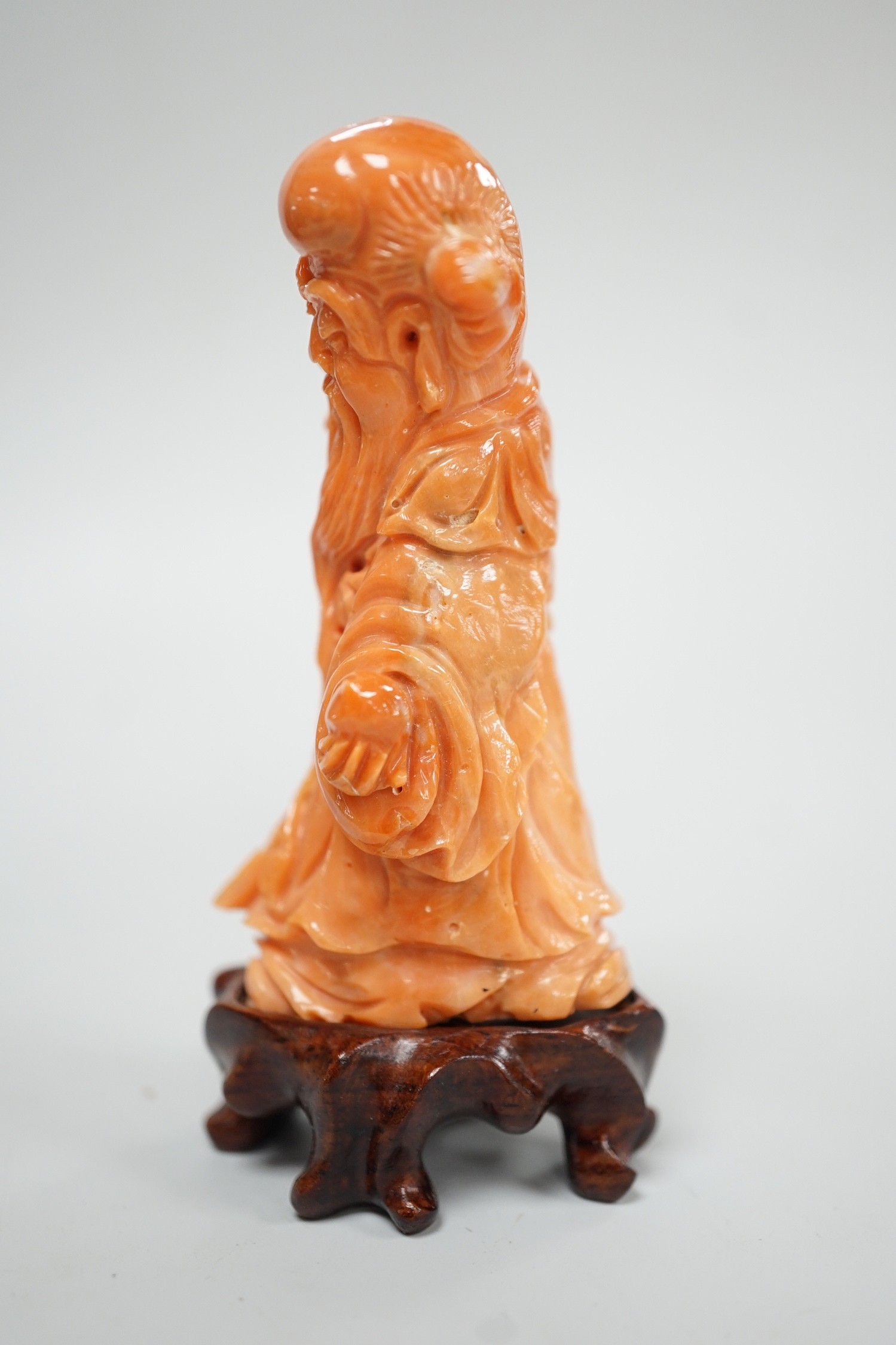 A Chinese coral figure of Shou Lao, 20th century, 7.4 cm high, 73g, wood stand